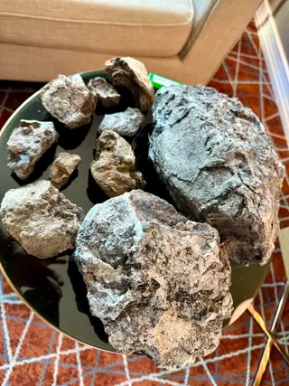The blue-grey ambergris lot piled on a round black table over an orange rug
