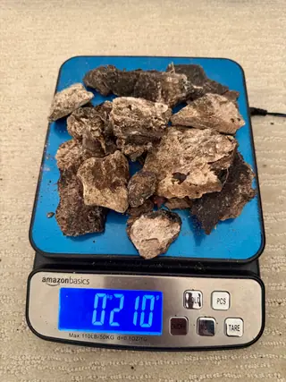 Smaller ambergris fragments from the sorted lot heaped on a blue digital scale