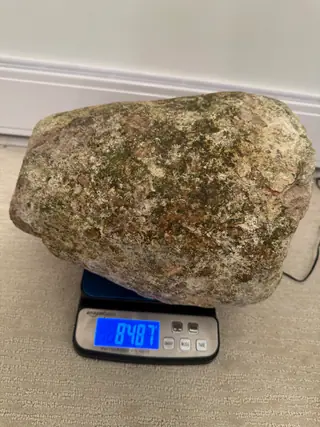 Another side of the very large grey and green ambergris piece on a digital scale
