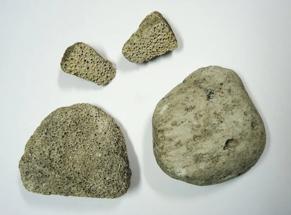 Four grey-green pumice stones, two of them broken open to show the holes
