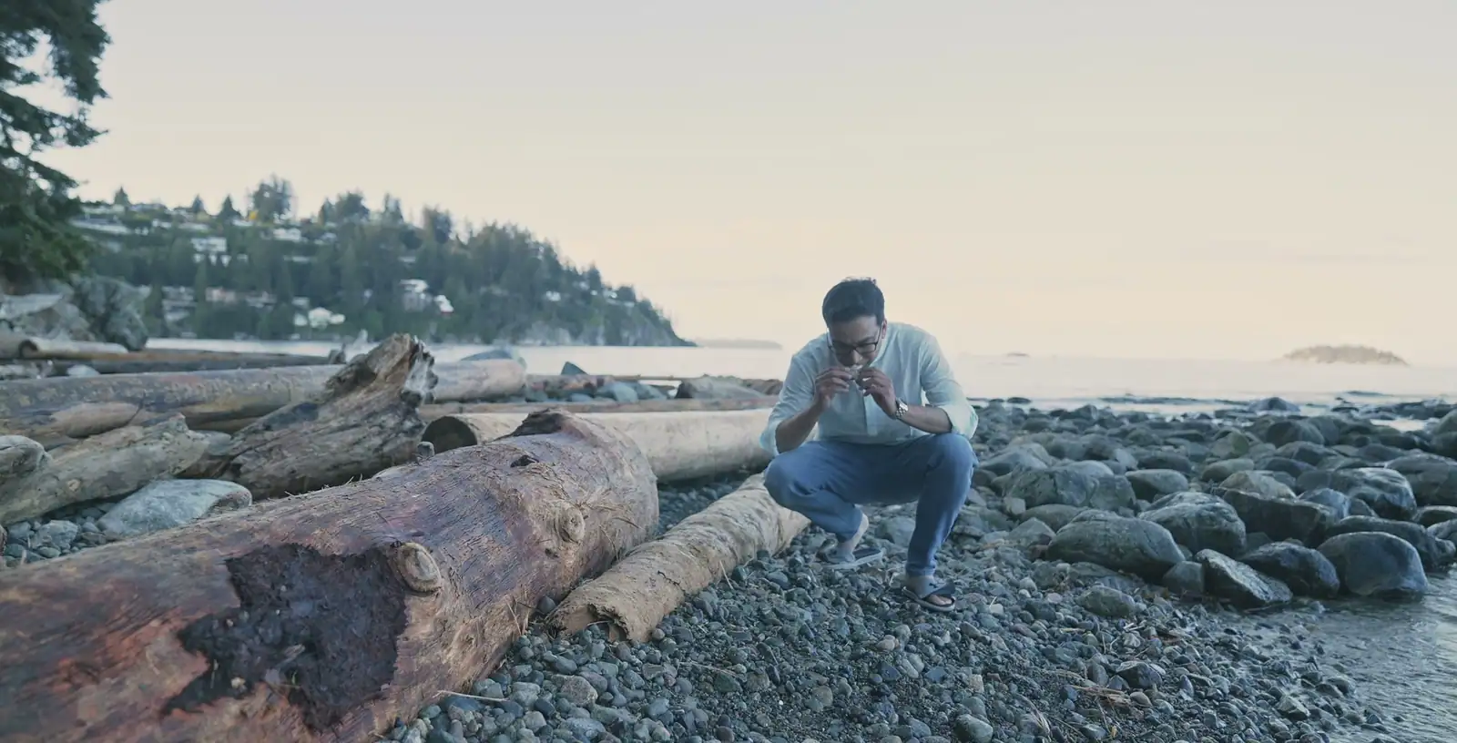 Nabil Valiulla examining a piece on a driftwood beach