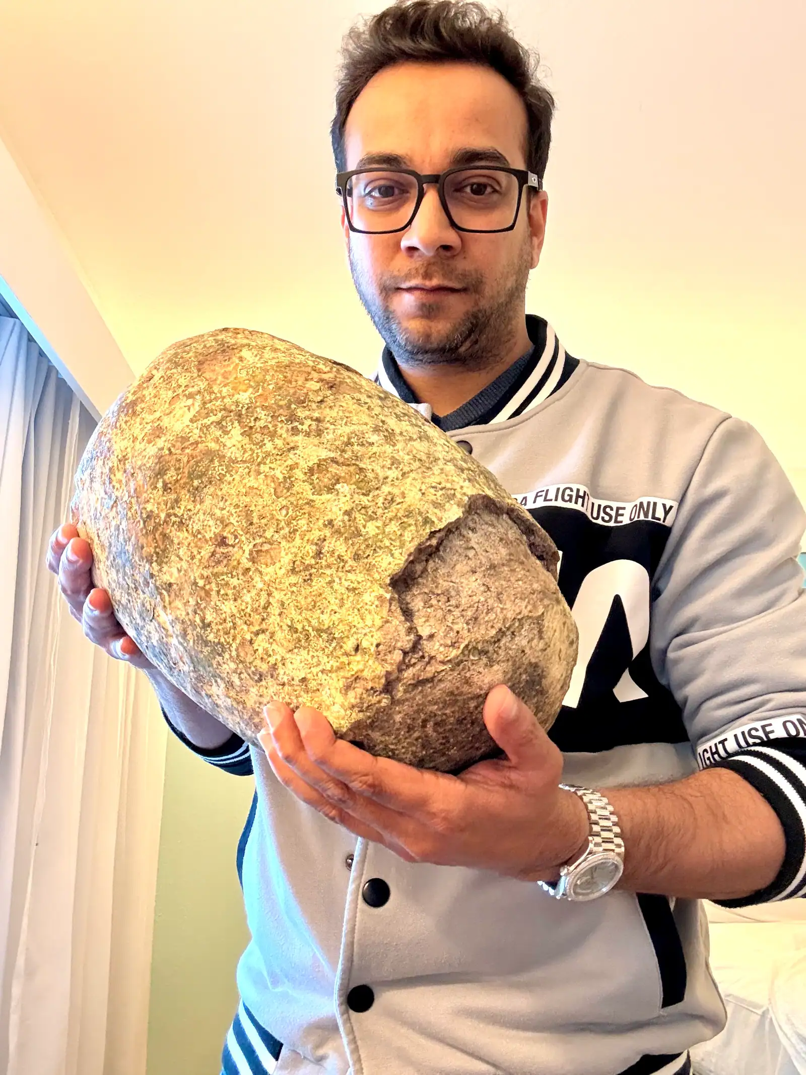 Nabil Valiulla holding a large grey ambergris boulder in both hands