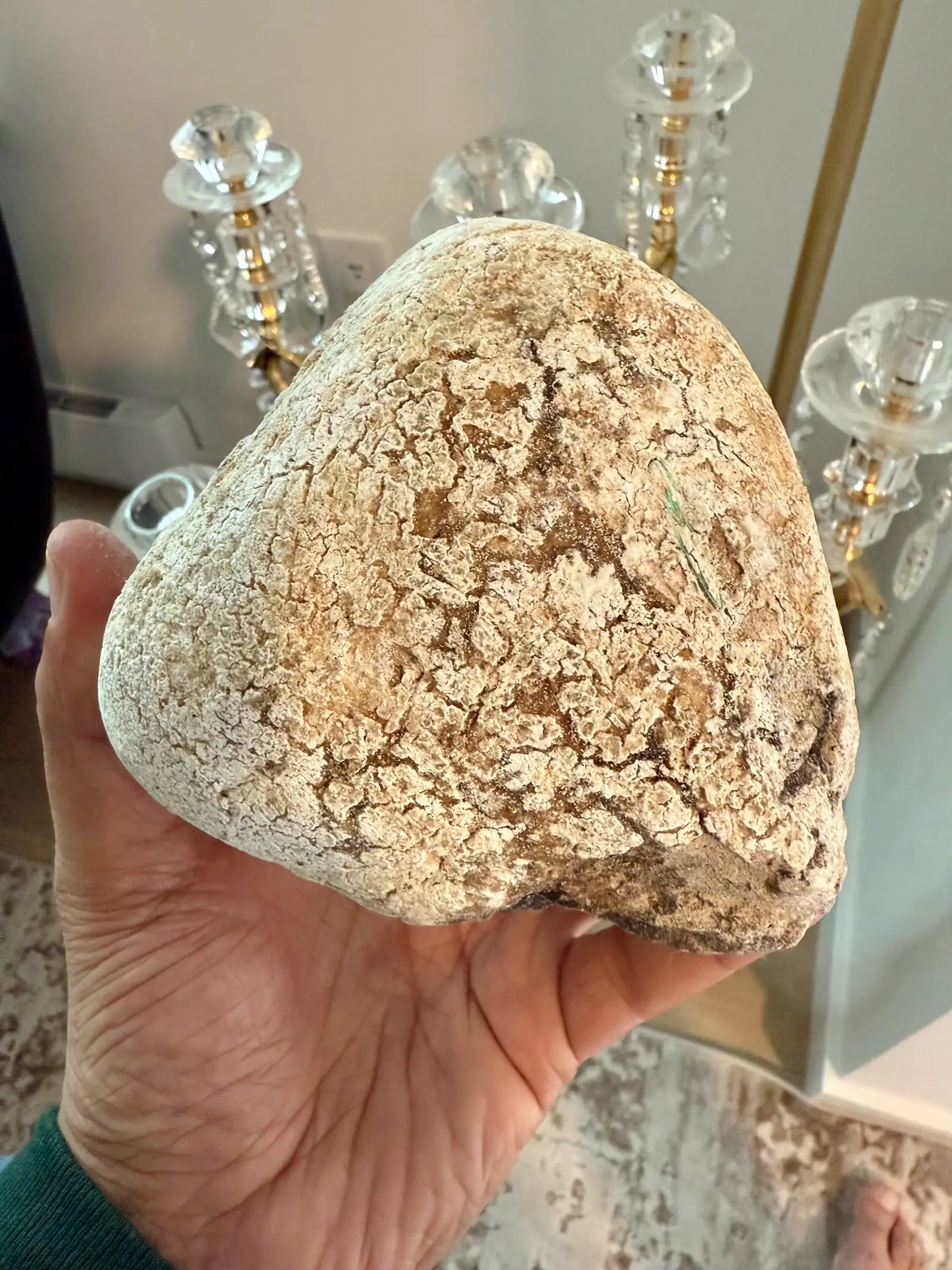 A rounded pale ambergris piece with tan crackle, in hand