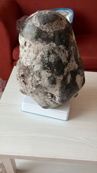 The other side of the tall mottled ambergris piece on a scale, a red sofa behind